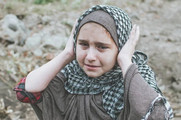 Un bambino rifugiato in guerra, una ragazza musulmana con una faccia sporca sulle rovine, il concetto di pace e guerra, il bambino piange e aspetta aiuto . — Foto Stock