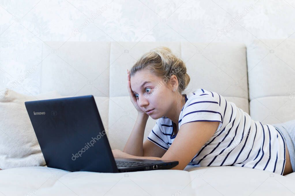 blonde girl is sitting at home on the couch with a laptop and communicates on the Internet. social networks. dating.