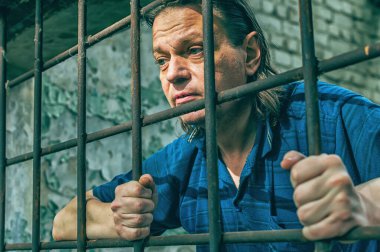 Depresyonda olan bir adam ellerini hapishane parmaklıklarında tutuyor. Suçun mahkumu. Kötü koşullar. Çığlık, umutsuzluk, acı, açlık.