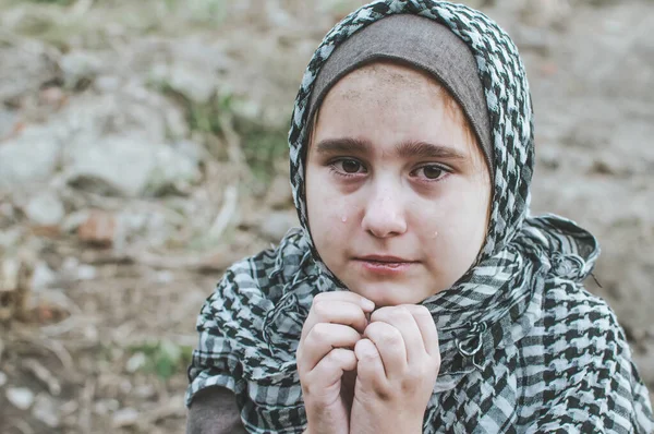 Un niño refugiado en la guerra, una niña musulmana con una cara sucia en las ruinas, el concepto de paz y guerra, el niño está llorando y esperando ayuda . — Foto de Stock
