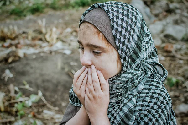 Ett flyktingbarn i kriget, en muslimsk flicka med ett smutsigt ansikte på ruinerna, begreppet fred och krig, barnet gråter och väntar på hjälp. — Stockfoto