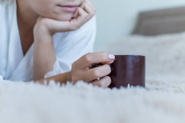 Sarışın, kahverengi bir fincandan kahve içer. Çıktı. dinlenme