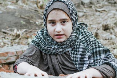 savaşta bir mülteci çocuk, harabeler üzerinde kirli bir yüzü olan Müslüman bir kız, barış ve savaş kavramı, çocuk ağlıyor ve yardım bekliyor.