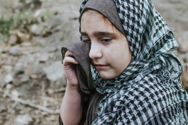 savaşta bir mülteci çocuk, harabeler üzerinde kirli bir yüzü olan Müslüman bir kız, barış ve savaş kavramı, çocuk ağlıyor ve yardım bekliyor.