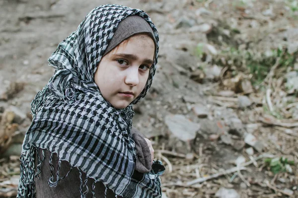 Un niño refugiado en la guerra, una niña musulmana con una cara sucia en las ruinas, el concepto de paz y guerra, el niño está llorando y esperando ayuda . — Foto de Stock