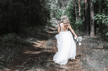 Beautiful bride blonde running through the woods alone. Wedding in the forest. clipart