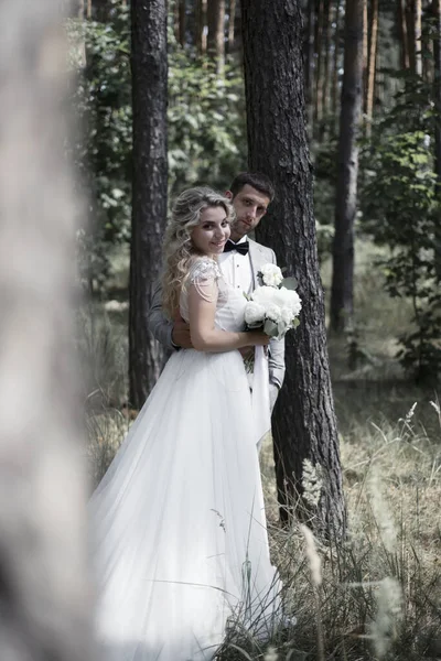 The bride and groom embrace in the forest on the wedding day. wedding ceremony. selective focus. film grain. — Stock Photo, Image