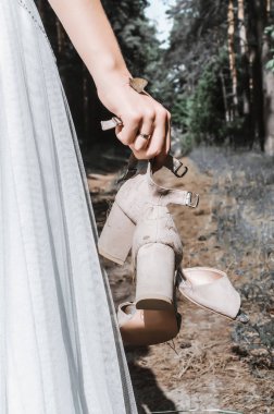 Gelin, kelebeğin oturduğu eli tutan ayakkabıları tutar. Düğün günü. Kapat..