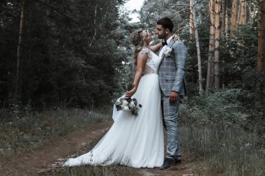 Gelin ve damat düğün günü ormanda kucaklaşırlar. Düğün töreni. Seçici odaklanma. film tahılı.