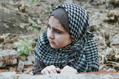 savaşta bir mülteci çocuk, harabeler üzerinde kirli bir yüzü olan Müslüman bir kız, barış ve savaş kavramı, çocuk ağlıyor ve yardım bekliyor.
