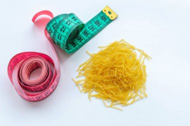 centimeter ribbon with macaroni on a white background. The concept of fighting excess weight.