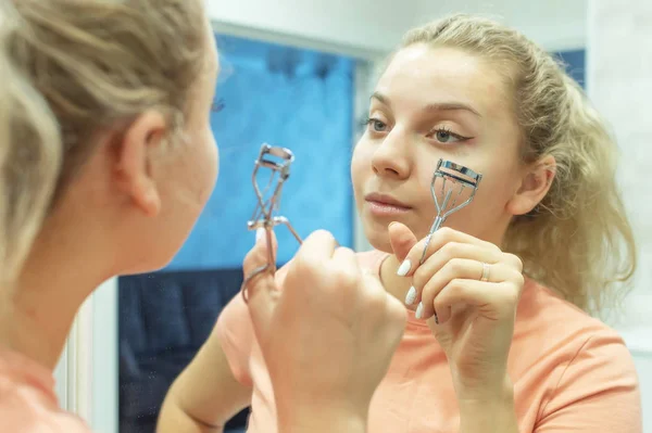 Kvinna korrigerar ögonfransar med locktång, närbild. Selektivt fokus, filmkorn. — Stockfoto