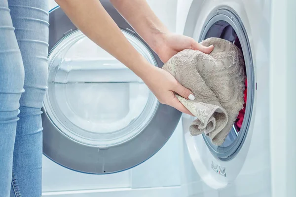 As mãos das mulheres põem a lavandaria na máquina de lavar roupa. Dama de casa. Fecha. Foco seletivo. Grãos de película — Fotografia de Stock