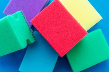 Kırmızı bulaşık süngerinin üzerindeki temizlik tozu çok renkli kürklerin yanında. Ev ödevi konsepti..