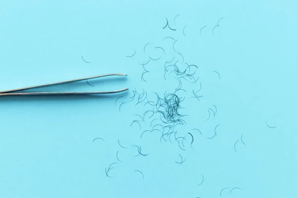 tweezers for plucking eyebrows and hair on a blue background with a place for writing