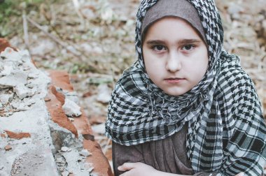 savaşta bir mülteci çocuk, harabeler üzerinde kirli bir yüzü olan Müslüman bir kız, barış ve savaş kavramı, çocuk ağlıyor ve yardım bekliyor.