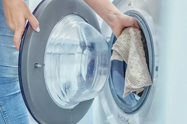 As mãos das mulheres põem a lavandaria na máquina de lavar roupa. Dama de casa. Fecha. Foco seletivo. Grãos de película — Fotografia de Stock