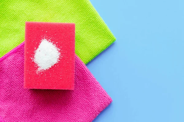 Cleaning powder on a red dishwashing sponge on a household towel on a pink background. The concept of homework.