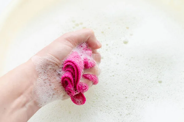 Pano de casa na mão sobre o fundo de sabão suds. O conceito de agregado familiar . — Fotografia de Stock