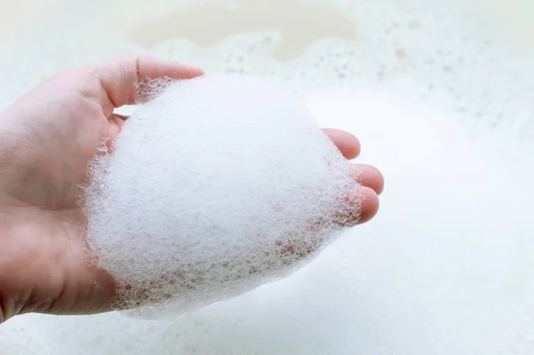 Tvål suger på en persons hand på en bakgrund av tvål suger. Begreppet renlighet och hygien. — Stockfoto