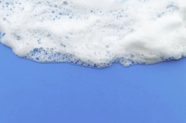 La textura de la espuma de jabón fluye hacia abajo desde arriba sobre un fondo lila. El concepto de higiene . — Foto de Stock