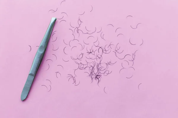 tweezers for plucking eyebrows and hair on a pink background with a place for writing