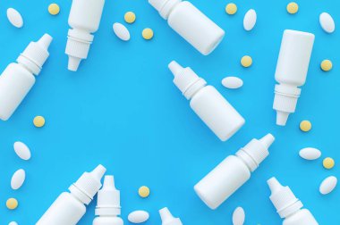 Burun damlası olan şişeler ve mavi arka planda yazacak bir yeri olan haplar. Yukarıdan görünüşü.