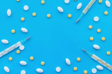 Mavi arka planda çok renkli haplar ve termometreler. Mesaj için de bir yer var. Yukarıdan manzara. Sağlık kavramı.