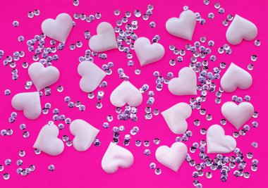 Texture. Satin pink hearts and sequins on a pink background. The view from the top. The concept of relationships and love.