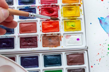 the human hand lowers the brush in watercolors. Art school. Close up.