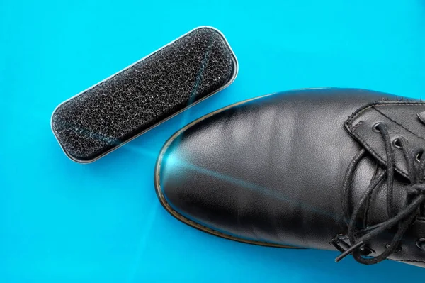 蓝色底色的擦亮的黑色皮靴旁边的擦鞋海绵 靠近点 — 图库照片