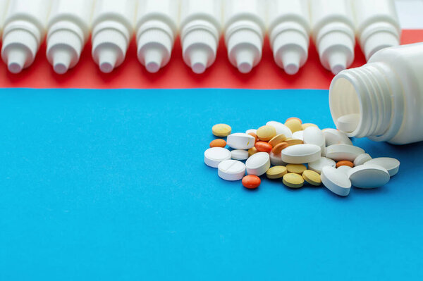 A jar of pills and Nosal drops on a blue and red background. Concept of health protection.