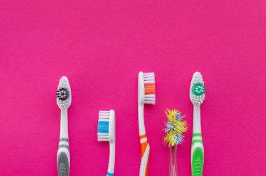 Çok renkli yeni diş fırçaları ve pembe arka planda eski bir diş fırçası. Yukarıdan manzara. Yakın çekim. Diş sağlığı kavramı..