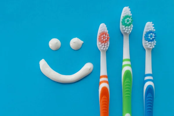 Escovas Dentes Multicoloridas Fundo Azul Com Sorriso Pintado Com Pasta — Fotografia de Stock
