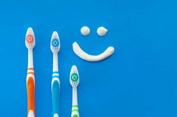 Escovas Dentes Multicoloridas Fundo Azul Com Sorriso Pintado Com Pasta — Fotografia de Stock