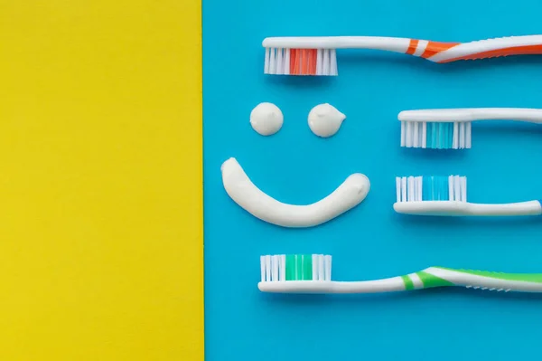 Multicolored Toothbrushes Blue Yellow Background Smile Painted Toothpaste View Top — Stock Photo, Image