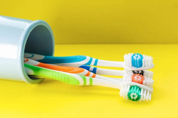 Escovas Dentes Multicoloridas Vidro Azul Fundo Amarelo Close Conceito Saúde — Fotografia de Stock