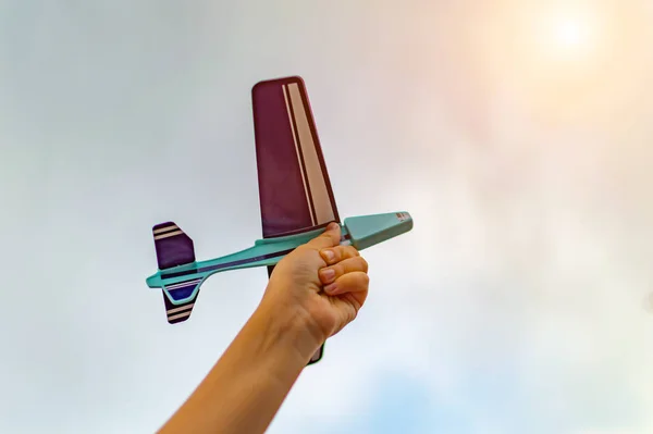 在阳光的天空中 一个小孩手里拿着一架玩具飞机 靠近点薄膜颗粒 有选择的重点 — 图库照片