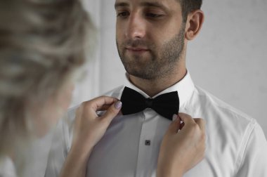 Gelin ve damadın sabahı. Gelin, düğün günü damadı giydirmeye yardım eder. seçici odaklanma. Film tahılları.