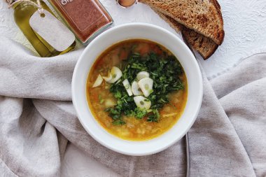 Masadaki beyaz kasede sarımsaklı mercimek çorbası ve otlar. Diyet, ev yapımı yemekler. Yukarıdan görünüşü.