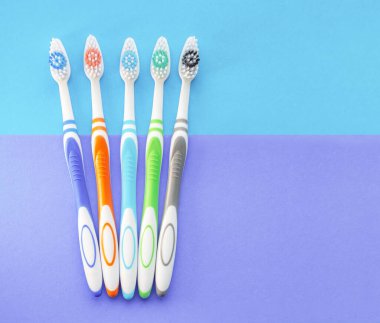 Mavi ve leylak arkaplanlı çok renkli diş fırçaları. Yukarıdan manzara. Diş sağlığı kavramı.