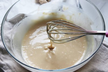 Büyük bir cam kasede çırpıcıyla vuruyor. Ev yapımı kek. Karantina döneminde ödev kavramı. Kapat..