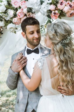 Gelin ve damat düğün gününde düğün kemerinde kucaklaşırlar. Seçici odaklanma. film tahılı.