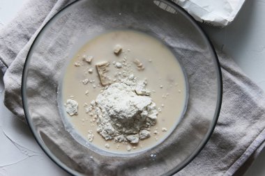 Un, maya ve süt büyük bir cam kasede. Ev yapımı kek. Karantina döneminde ödev kavramı. Kapat..