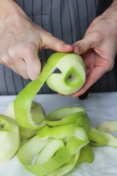 Mãos Cozinheiro Descascam Uma Maçã Verde Com Uma Faca Bolo — Fotografia de Stock