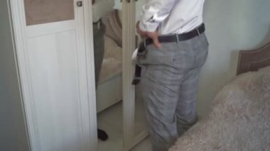 Bir adam işten önce giyinir, damat düğünden önce giyinir, aynaya bakar.