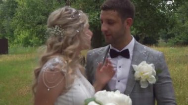 Gelin ve damat yaz mevsiminde yeşil bir parkta yürüyüşe çıktılar.