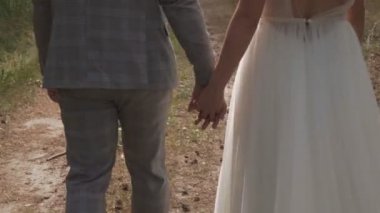 Gelin ve damat yaz mevsiminde yeşil bir parkta yürüyüşe çıktılar.