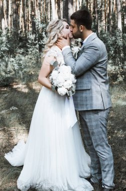 the bride and groom kiss in the forest at the wedding ceremony. selective focus. film grain.