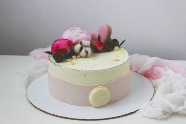 Masanın üzerinde şakayık ve makarna olan pembe kremalı pasta. Doğum günü hediyesi. Seçici odaklanma. Kapat..